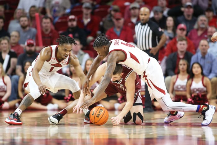 Razorback fans sit in their seats calmly observing Arkansas Razorbacks guards JD Notae (1) and Davonte Davis (4) scrapping with South Carolina Gamecocks guard Erik Stevenson (10) for control of the loose ball they knocked away with active defense in the second half at Bud Walton Arena. Arkansas won 75-59.